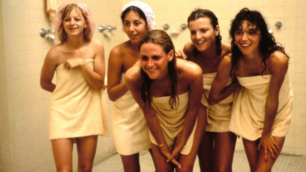 Cena do filme Porky's - A Casa do Amor e do Riso. Em um banheiro as atrizes do filme estão só de toalha, olhando para frente e sorrindo. 