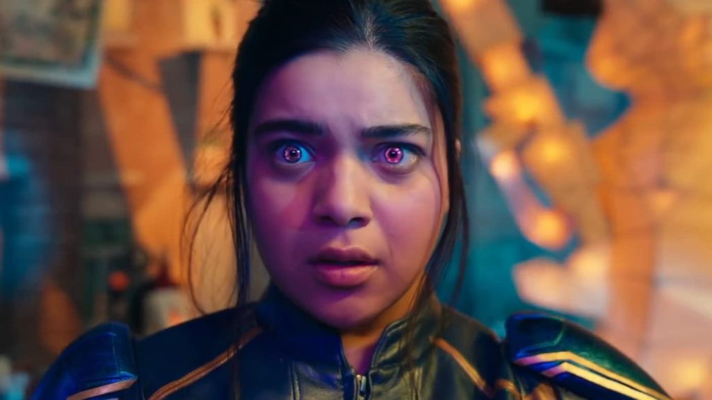 Imagem mostra a personagem Kamala Khan, da série Ms. Marvel, com os olhos arregalados e multicoloridos em roxo. Ela está assustada.