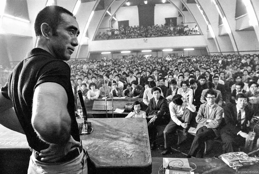 Mishima em palanque, universidade, falando para diversos estudantes.